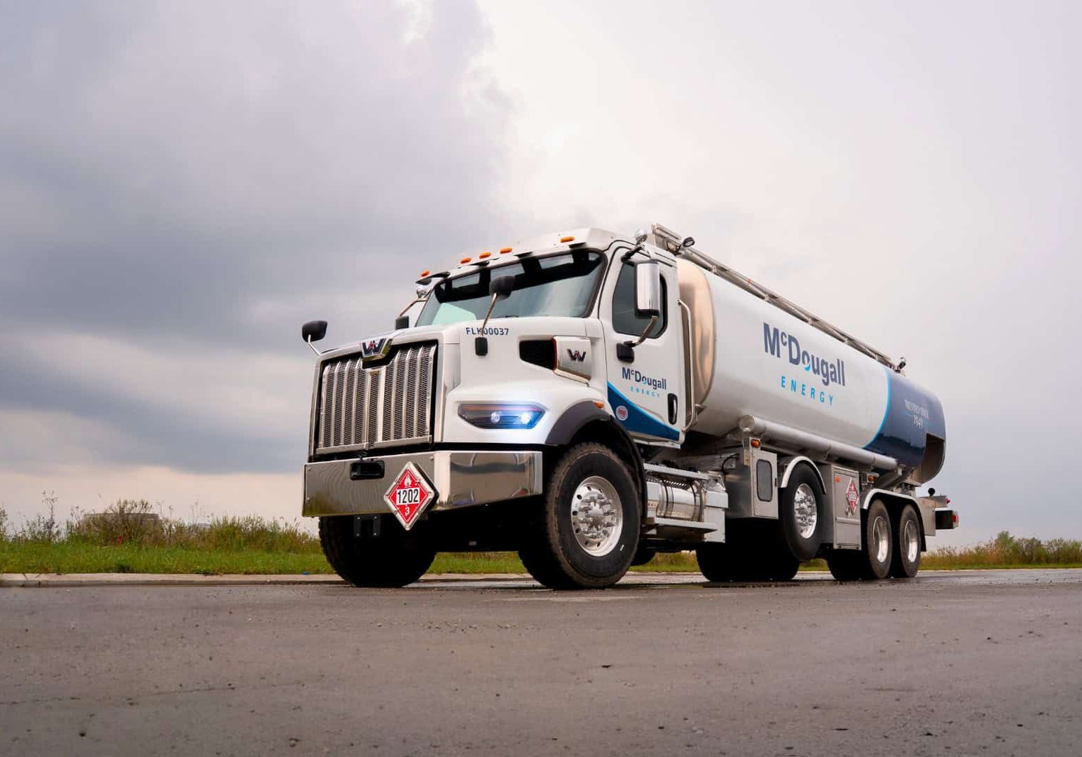 Fuel delivery truck delivering fuel as part of McDougall Energy promotions on a rural road.